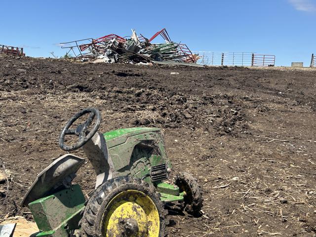 A toy tractor sits on the edge of the Queck farm west of Orient, Iowa with a pile of debris in the background where a cattle barn used to stand. The farm was destroyed by the May 21 EF-4 tornado. (DTN photo by Jennifer Carrico)