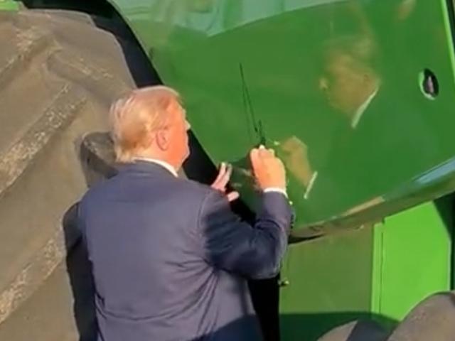 Former President Donald Trump signing a John Deere combine at a farm event in Iowa in October 2023. On Monday, Trump warned Deere the machinery manufacturer would face a 200% tariff for machinery imported from Mexico. (Image from video livestream)